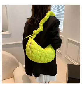 Close-up detail of the neon yellow quilted croissant bag with pleated shoulder strap