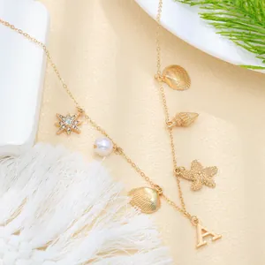 Detail view of gold ocean-themed necklace with shells, pearl, and letter A charm
