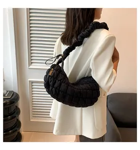 Detailed shot of a black quilted pleated dumpling bag worn by model in white blazer
