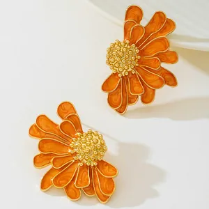 Detailed view of orange enamel daisy earrings with gold-toned textured flower centers