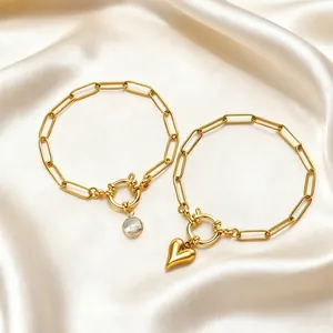 Detail view of 18K gold plated stainless steel paperclip bracelets with heart charms.
