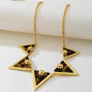 Close-up of gold-toned necklace featuring triangular leopard print pendants and beads