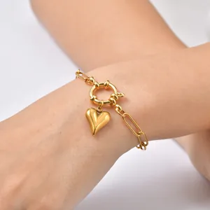 Detail view of a 18K gold plated stainless steel heart charm bracelet on a wrist