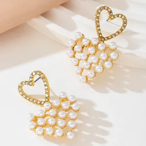 Detail view of gold heart earrings with white pearls and sparkling rhinestones