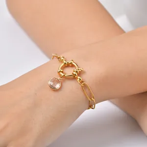 Detail view of a gold-plated stainless steel bracelet with a clear zircon pendant.