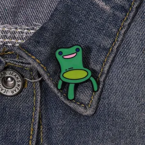 Detail shot of cute green cartoon frog chair enamel pin on denim jacket lapel