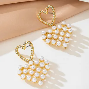 Detail view of gold heart earrings with white pearls and sparkling rhinestones