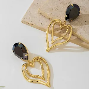 Close-up of golden heart-shaped drop earrings with elegant black teardrop resin stones