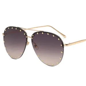 Close-up detail of oversized aviator sunglasses with gold studs and gradient lenses.