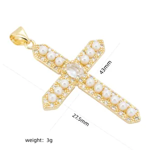 Vue détaillée d'un pendentif en forme de croix en cuivre doré avec zircons et perles.