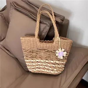 Detailansicht einer handgewebten Strohtasche mit Blumenanhänger für den Strandurlaub