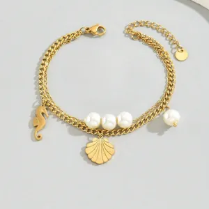 Close-up detail of a gold layered stainless steel bracelet featuring shell charms and pearls