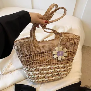Große handgefertigte Stroh-Strandtasche mit dekorativem Blumenanhänger im Detail