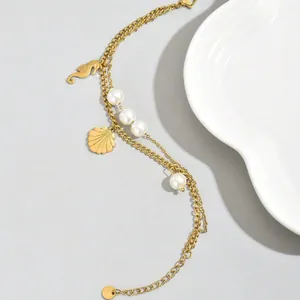 Detail of gold layered bracelet featuring pearls, seahorse and scallop shell charms.