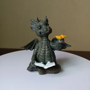 Detailed view of a cute resin dragon figurine reading a book with a yellow flower.