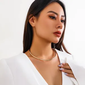Detail view of a minimalist smooth gold metal choker necklace on a female model
