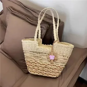 Detaillierte Ansicht der Webstruktur und des Schmetterlingsanhängers dieser Stroh-Strandtasche
