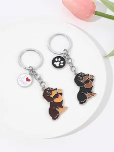 Detail view of cute waving dachshund dog keychains in black and brown enamel