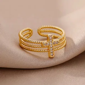 Detailed view of micro-set zircon cross charm on a gold triple beaded open ring