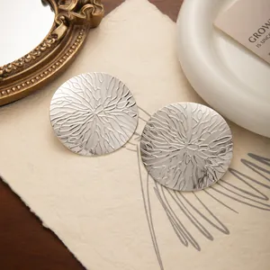 Détail macro de boucles d'oreilles rondes argentées avec une texture rétro soleil