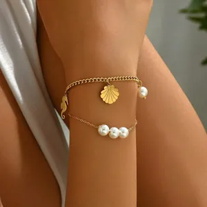 Detailed view of gold stainless steel layered bracelet with pearls and shell charm