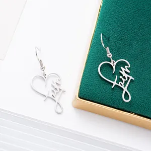 Close-up of stainless steel heart earrings featuring the word "Faith" in a script font.
