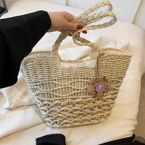 Detailansicht einer großen Stroh-Strandtasche mit einem lila Schmetterlingsanhänger