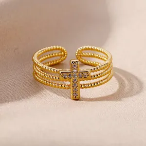 Detail of triple-layer beaded gold ring featuring a sparkling zircon-set cross.