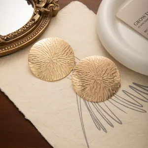 Gros plan de boucles d'oreilles dorées en métal avec texture soleil vintage