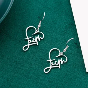 Close-up view of stainless steel heart drop earrings with faith script engraving