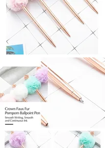 Close-up of rose gold metal ballpoint pen with crown and plush pom-pom detail