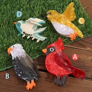 Cute bird-shaped acetate hair claw clips with colorful marble texture on grass background
