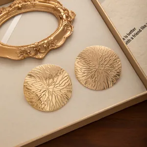 Gros plan de boucles d'oreilles dorées texturées vintage dans un coffret cadeau.