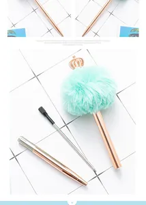 Detailed view of rose gold metal ballpoint pen with mint green fur pom-pom and crown.