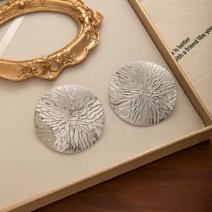 Gros plan de boucles d'oreilles rondes argentées avec texture ondulée en relief