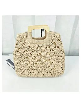 Detailed view of handmade woven straw bag featuring square wooden handles and shell patterns.