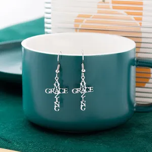 Close-up of silver stainless steel cross earrings with Amazing Grace hollow design
