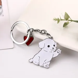 Close-up detail of a cute white cartoon waving dog keychain with a red heart charm