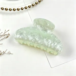 Detail of light green marbled acrylic hair claw clip with water ripple texture.