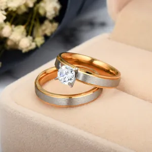Close-up of two-tone matte stainless steel couple rings with a four-prong cubic zirconia