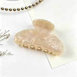 Detailed macro view of an acrylic hair claw clip featuring cream pearl marble texture