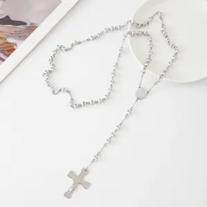 Detail view of a stainless steel rosary necklace with white beads and a cross pendant