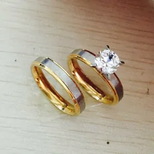 Close-up of two-tone stainless steel couple rings with matte finish and four-claw zircon