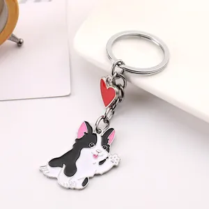 Close-up of a cute waving black and white dog keychain with a red heart pendant.