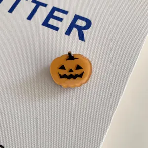 Macro detail of a cute orange pumpkin acrylic hair clip for Halloween party decor.