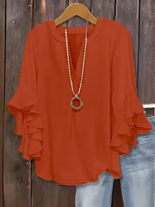 Detail view of orange V-neck blouse with elegant tiered ruffle sleeves and casual fit