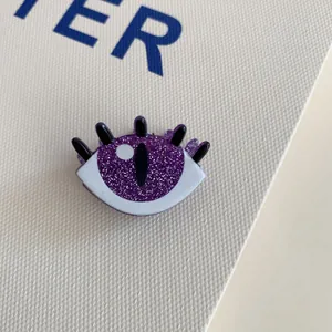 Macro detail of a purple glittery eye-shaped Halloween acrylic mini claw hair clip
