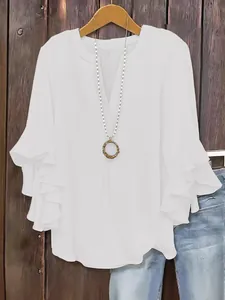 Close-up detail of white loose V-neck blouse featuring tiered ruffled three-quarter sleeves
