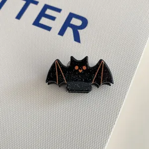 Close-up of a black acrylic bat hair clip with orange eyes and silver glitter details
