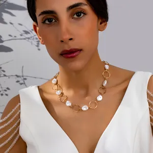 Detailed view of elegant baroque pearl necklace with gold links worn by a model in white dress.